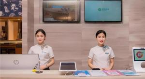 two women standing in front of a table with a laptop at City Comfort Inn Liuzhou Wuxing Walking Street Zhonghuan Tower in Liuzhou