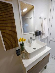 a bathroom with a sink and a mirror and yellow flowers at Bodokia winery and guesthouse in Gegut'i