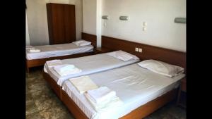 two beds in a hotel room with white sheets at Paradise Studios in Faliraki