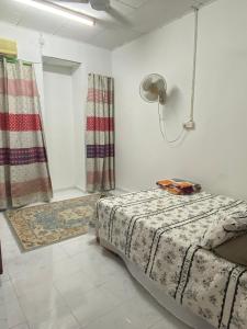 a bedroom with a bed and a lamp and curtains at imani homestay taman ira kangar perlis in Kangar