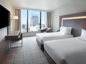a hotel room with two beds and a large window at Novotel Bangkok Platinum Pratunam in Bangkok