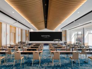 a dining room with tables and chairs and a projection screen at Novotel Bangkok Platinum Pratunam in Bangkok