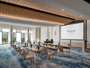 a conference room with tables and chairs and a screen at Novotel Bangkok Platinum Pratunam in Bangkok