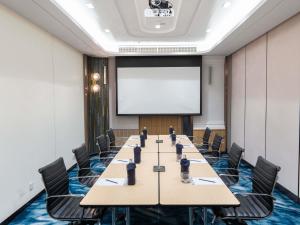 a conference room with a long table and a projector screen at Novotel Bangkok Platinum Pratunam in Bangkok