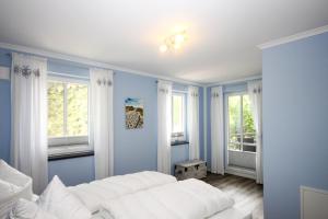 Un dormitorio con una cama blanca y dos ventanas. en Haus Pamir - Ferienwohnungen, en Ostseebad Nienhagen