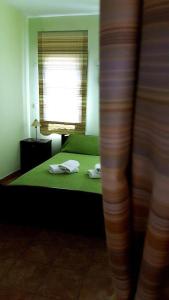 a bedroom with a green bed with a window at Pension Anastasia in Ammouliani