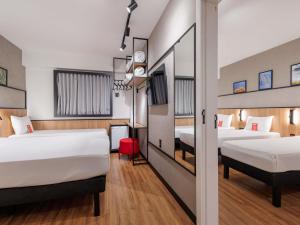 a hotel room with two beds and a hallway at Ibis Foz do Iguaçu in Foz do Iguaçu