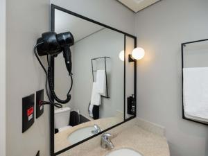 a bathroom with a large mirror over a sink at Ibis Foz do Iguaçu in Foz do Iguaçu +61 photos