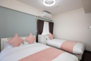 Dos camas en un dormitorio con rosa y blanco. en Ocean Smile, 