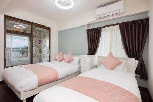 2 camas en un dormitorio con ventana en Ocean Smile,  63 fotos más