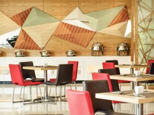 a restaurant with tables and chairs and geometric ceilings at Ibis Balikpapan in Balikpapan +53 photos