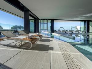 a swimming pool with several beds in a building at La Grande Terrasse Hotel & Spa La Rochelle - MGallery Collection in Châtelaillon-Plage
