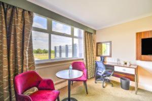 a hotel room with a table and chairs and a window at Palms Hotel & Retreat By Palette London Romford in Hornchurch