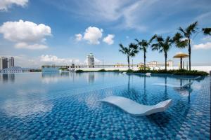 a swimming pool with a white chair in the water at Metropol by BRB in Bukit Mertajam