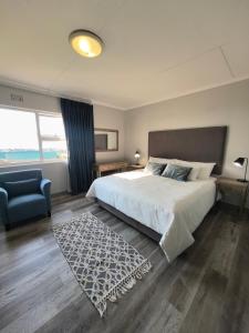 a bedroom with a large bed and a blue chair at Harmonie in Hartenbos in Mossel Bay