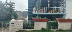 a building with a fence with potted plants on it at VHP luxury cottage kodaikkanal in Kodaikānāl