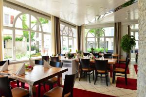 a restaurant with tables and chairs and windows at Lobinger Hotel Weisses Ross & Restaurant in Langenau