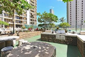 a patio with a table and chairs and buildings at Waikiki Banyan Ohana Suite in Honolulu