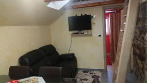 a living room with a black leather couch and a flat screen tv at Apartment Borovnica Rogla in Resnik