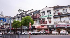 una strada cittadina con auto parcheggiate davanti agli edifici di GreenTree Inn Express Suzhou Luzhi Ancient Town Scenic Area Xiaoshi Road a Suzhou