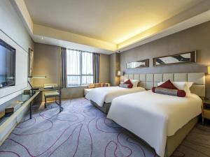 a hotel room with two beds and a flat screen tv at Grand Mercure Jinan Sunshine in Jinan +86 photos