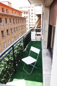 una silla blanca en un balcón con césped verde en Roomin Hostel, en Salamanca