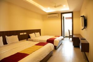a hotel room with two beds and a television at Heritage By High Point in Tiruchchirāppalli +15 photos
