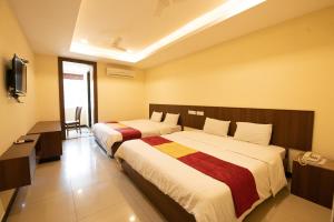a hotel room with two beds and a television at Heritage By High Point in Tiruchchirāppalli