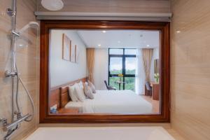 a mirror in a bathroom with a bed and a shower at Golden Mountain Hotel Phu Quoc in Phú Quốc