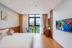 a hotel room with a bed and a desk and a window at Golden Mountain Hotel Phu Quoc in Phú Quốc
