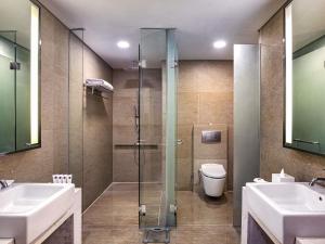 a bathroom with a shower and two sinks and a toilet at Grand Mercure Jakarta Harmoni in Jakarta