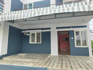 een blauw-wit huis met een rode deur bij Nandi Parihar Villa 1 in Bangalore
