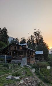 a wooden house on a hill with the sunset in the background at Mirvana home stay in Kalgha