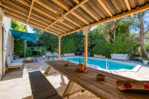 une terrasse avec une table en bois et une piscine dans l'établissement Maison Sur La Mare, à Villemagne