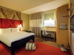 a hotel room with a bed and a desk and a window at Ibis Hamburg City in Hamburg