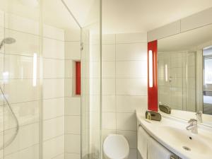 a bathroom with a shower and a toilet and a sink at Ibis Hamburg City in Hamburg