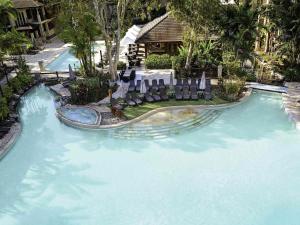 una piscina con sedie e uno scivolo in un resort di Pullman Palm Cove Sea Temple Resort & Spa a Palm Cove
