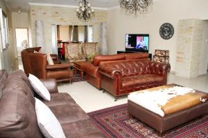 a living room with leather furniture and a tv at Black Horses Lodge & Conferencing in Vryheid