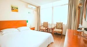 a hotel room with a bed and a table and chairs at GreenTree Inn Yangzhou Slender West Lake Wencheng Attic Express Hotel in Yangzhou