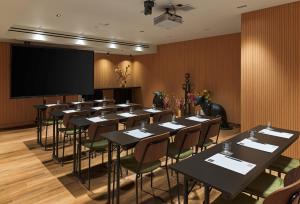 a conference room with tables and chairs and a projection screen at NYX Hotel Thessaloniki in Thessaloniki