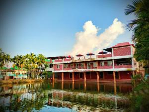 a red building next to a body of water at Mukta Nagar Resort in Pitua