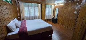 ein Schlafzimmer mit einem Bett in einem Holzzimmer in der Unterkunft The Hillscape in Darjeeling