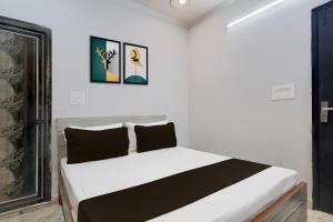 a bedroom with a white bed with black pillows at Hotel O Vishal plaza in New Delhi