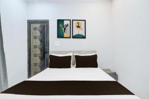 a bedroom with a white bed with three pictures on the wall at Hotel O Vishal plaza in New Delhi