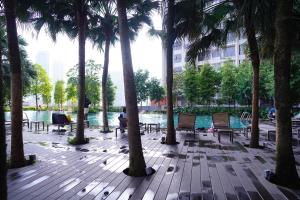 クアラルンプールにあるAgile Residence Bukit Bintang by Skyline Homesのプールの横にヤシの木と椅子のあるパティオ