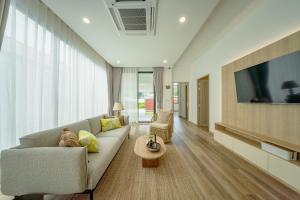 un salon avec un canapé et une télévision dans l'établissement New 3BR Pool Villa w Jacuzzi Ao Nang Krabi, à Ban Khlong Haeng