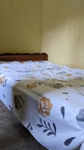 Una cama con una manta blanca con flores. en Akagera Homestay Experiences, en Rwinkwavu
