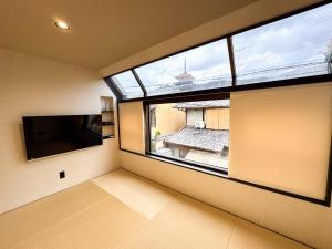 um quarto com 2 janelas grandes e uma televisão de ecrã plano em Rinn Yumemizaka Yumeko em Quioto