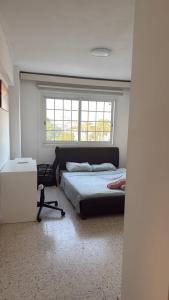 un dormitorio con una cama y una ventana en Larnaca Ancient View Rooms, en Lárnaca