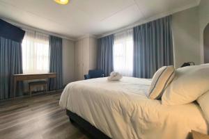 a bedroom with a large white bed with blue curtains at Harmonie in Hartenbos in Mossel Bay +88 photos